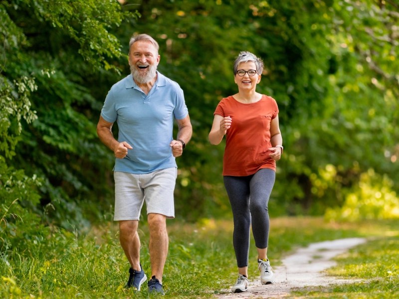 An older couple walking briskly along a park path