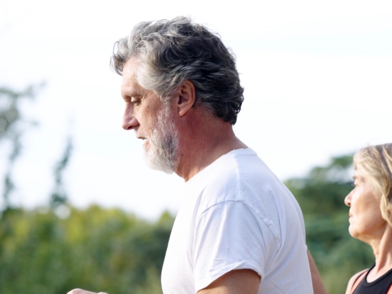 A grey-haired man out on a run in the park
